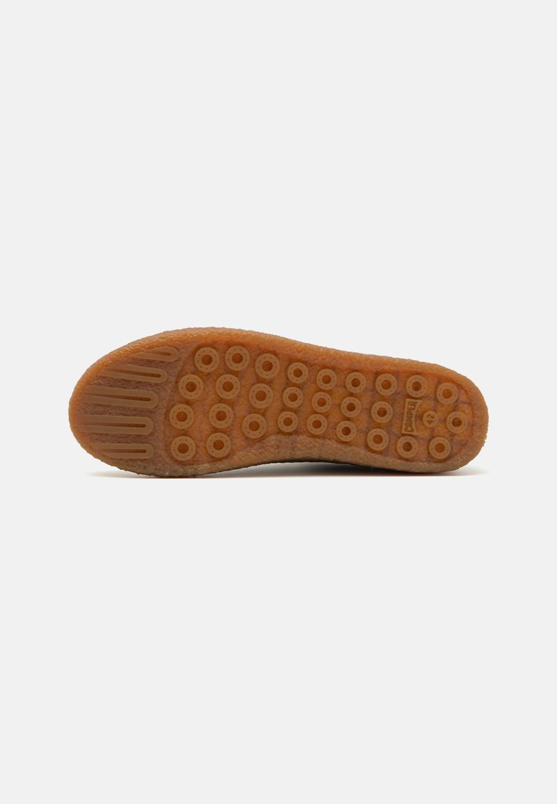 Rubber shoe sole with a textured surface, featuring circular traction patterns and ridged sections, in brown and tan colors.