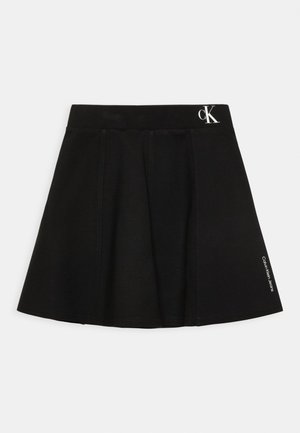 Czarna spódnica w kształcie litery A z logo Calvin Klein na pasku i małym napisem po boku, jednolite tło.