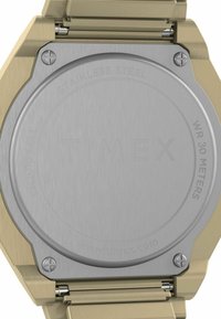 Tylnia część zegarka Timex z wypolerowaną stalą nierdzewną, wyraźnymi grawerunkami i kopertą w kolorze złota. Wodoodporny do 30 metrów.