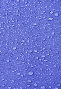 Tessuto viola resistente all'acqua con una superficie texturizzata, caratterizzato da numerose piccole gocce d'acqua distribuite uniformemente sulla materia.