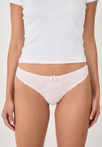 Tanga de algodón rosa con encaje, que presenta un detalle bordado de "Confianza" y un pequeño lazo en la cintura frontal.