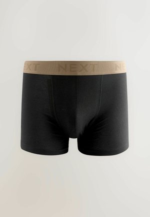 Zwarte boxershorts van rekbaar materiaal met een tankleurige tailleband waarop het woord "NEXT" in een herhalend patroon is gedrukt.
