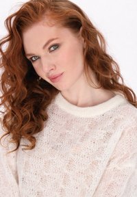 Leichtes Strickpullover in Creme mit strukturiertem Muster und geripptem Rundhalsausschnitt, der transparente Elemente und einen weichen Stoff präsentiert.