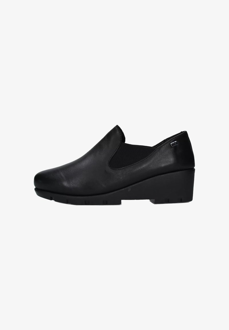 Scarpa slip-on in pelle nera con tacco basso a zeppa e pannelli elastici laterali per una facile vestibilità, progettata per comfort e supporto.