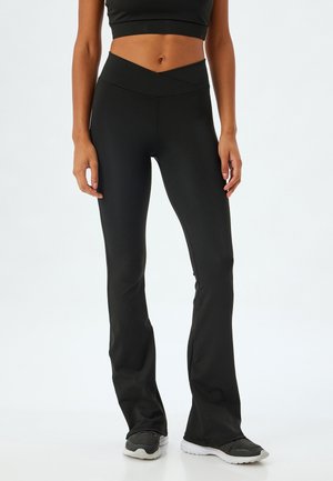 Czarne, dopasowane legginsy dzwonowe z wysokim stanem, gładką fakturą i ukośnym krzyżowym wzorem na pasie.