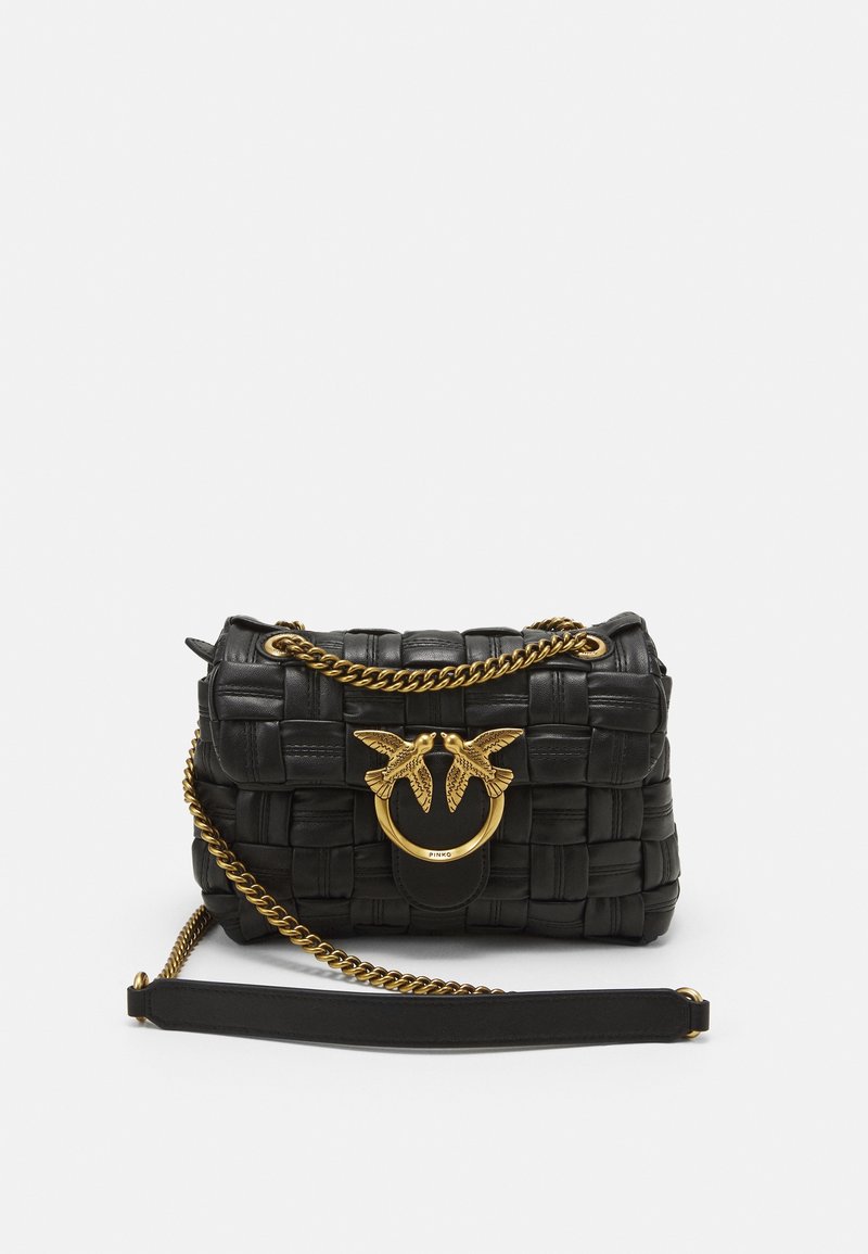 Sac à main en cuir tressé noir avec chaîne en or et emblème représentant deux oiseaux, forme structurée et bandoulière amovible.