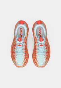 Αθλητικά παπούτσια Asics με επάνω μέρος σε ανοιχτό γαλάζιο χρώμα, διακοσμημένο με μοτίβο πιτσιλιών σε κόκκινο και πορτοκαλί, επίπεδα κορδόνια και επενδεδυμένο γιακά για άνεση.