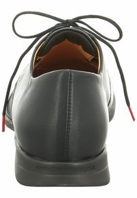Chaussure en cuir noir avec un talon arrondi, présentant une texture lisse, de fines lacets noirs et des accents rouges aux extrémités. Design simple et élégant.