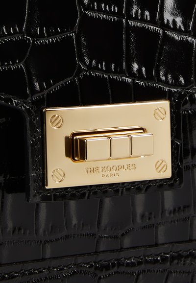 Borsa in pelle verniciata nera con texture a coccodrillo, hardware in tono dorato e chiusura rettangolare con nome del brand inciso.