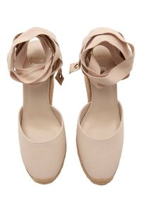 Des chaussures à talons compensés en toile beige clair avec des liens en tissu autour de la cheville, une doublure intérieure douce et une semelle en corde de jute naturel.