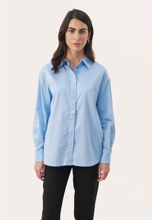 Camicia azzurro chiaro con maniche lunghe, colletto classico e taglio dritto. Tessuto liscio con dettagli di consistenza minimi.