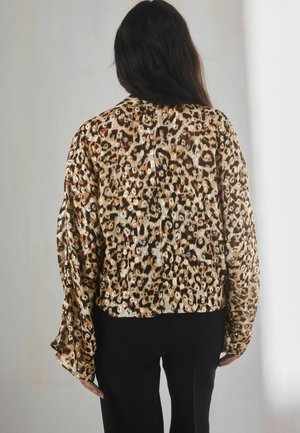 Bronze leopard-print blouse with a loose fit, long sleeves, and a cinched hem. The material has a shiny texture and contrasting black accents.