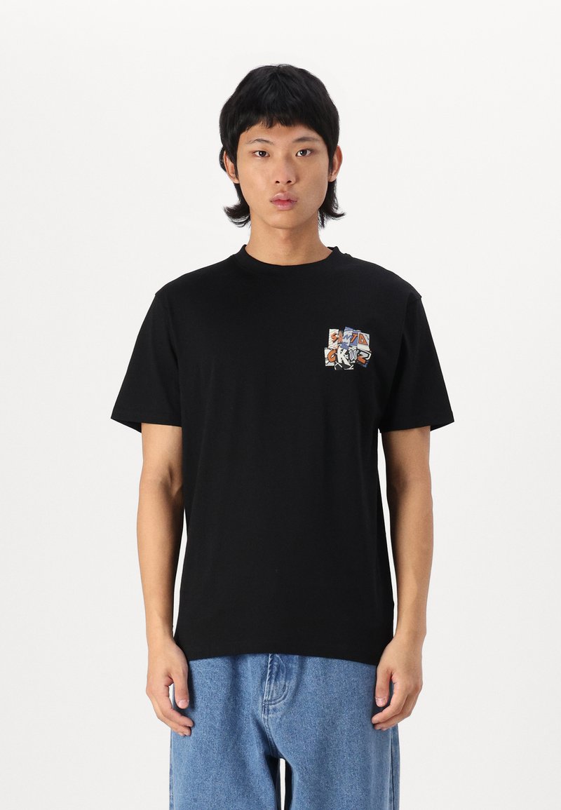 Schwarzes Baumwoll-T-Shirt mit Rundhalsausschnitt, das ein mehrfarbiges Grafik-Patch auf der linken Brust hat. Kurze Ärmel und lockere Passform.
