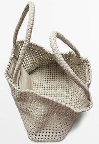 Geweven totebag in beige, met twee gevlochten handvatten, een ruime binnenkant en een subtiele textuur met een ritsvak binnenin.