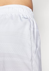 Weiße Sportshorts mit elastischem Bund, die subtile gepunktete und gestreifte Muster aufweisen. Enthält das "Climacool"-Label an der Seite.