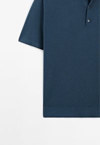 Mørkeblå kortærmet polo skjorte lavet af tekstureret stof, med ribbet krave og kant, samt detalje med to knapper ved åbningen.