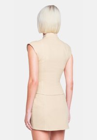 Beige ärmelloses Kleid mit hohem Ausschnitt, tailliertem Oberteil und schwingendem Rock. Sichtbare Nähte sorgen für Textur.