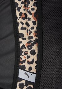 Mustekki musta kangas, jossa on sivupaneeli, jossa on leopardikuosi vaaleanruskeana ja mustana. Mukana on pieni hopeinen logotagi, jossa on hyppäävä pantteri.