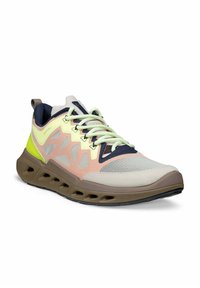 Lichtgewicht sportschoen met een bovenwerk van beige, perzik, marineblauw en neon geel mesh, een unieke bruine zool met ventilatiegaten en lichtgroene veter.