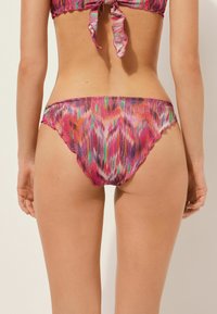 Vícebarevné spodní díly bikiny s růžovým, fialovým a duhovým vzorem. Disponuje vykrojenými okraji a hladkým, elastickým materiálem.