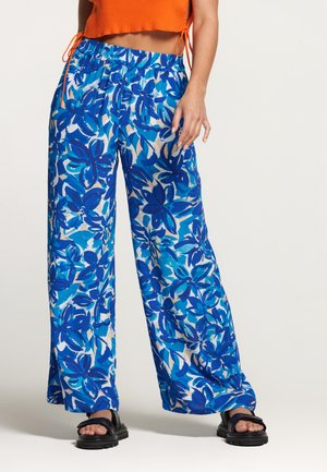 Stijlvolle, wijde broekspijpen met een levendig blauw bloemenpatroon op een witte achtergrond, uitgerust met een elastische tailleband en van een zachte stof.