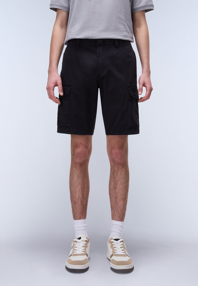 Shorts cargo noirs avec deux poches latérales, en tissu coton, à coupe régulière et avec fermeture à bouton, associés à des baskets beiges.