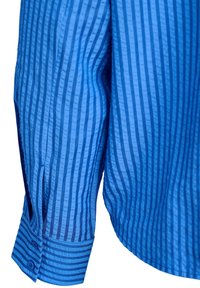 Modrá košile s rukávem, který má svislé a vodorovné proužkované vzory, knoflíkové manžety a viditelné detaily švů.