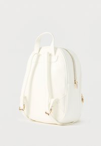 Zaino in ecopelle bianca con spallacci regolabili, manico superiore, dettaglio cerniera dorata e forma arrotondata; texture liscia, design minimalista.