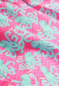 Mintás szövet, világoskék polipokkal egy élénk rózsaszín háttéren, zigzag mintázattal. A textúra simának és színesnek tűnik.