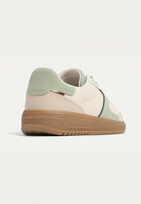 Textured beige sneakers with mint green accents and a light brown rubber sole, featuring a smooth finish and subtle detailing.