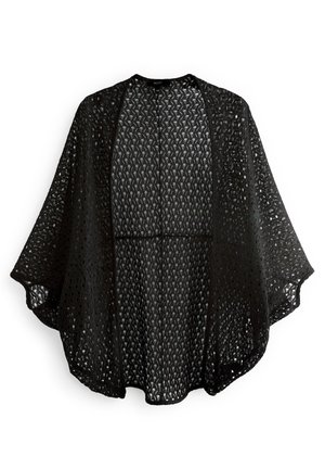 Châle noir en crochet à ouverture frontale, manches larges et design ample et fluide sur fond blanc.