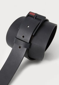 Curea din piele neagră cu finisaj mat, cataramă rectangulară cu accent roșu și mai multe găuri pentru ajustarea mărimii.