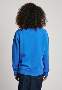 Felpa in cotone blu con scollo rotondo, maniche raglan e polsini e orlo a costine. Texture liscia con una vestibilità comoda.