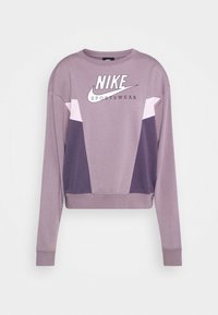 Nike sportströja i ljuslila med geometrisk färgblockering i mörkare nyanser, med rund hals och logotryck på bröstet.