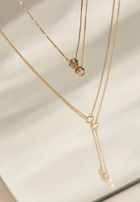 Chaînes délicates en or à plusieurs couches avec un petit pendentif en diamant et une chute en forme de Y ornée de trois petites perles.