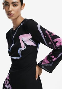 Schwarzes Kleid mit abstrakten pinken und blauen Mustern. Lange Ärmel mit grafischen Details. Glatte Textur und taillierter Schnitt.
