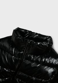 Giacca a vento nera con finitura lucida, colletto alto e cerniera anteriore parziale. Il materiale presenta una texture trapuntata e dettagli lisci.