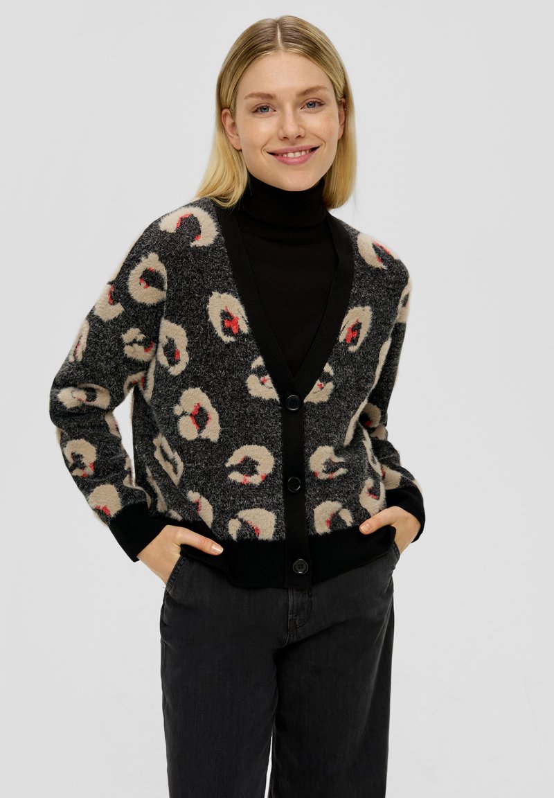 Zwart- en crèmekleurig luipaardprint cardigan met een V-hals, knopen aan de voorkant en geribbelde manchetten, gedragen over een zwarte coltrui. Zachte, gestructureerde stof.