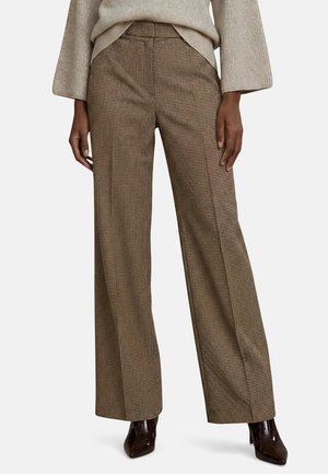 Pantalon large à motif pied-de-poule marron et beige porté avec un pull beige en maille côtelée et des bottines à bout pointu marron foncé.