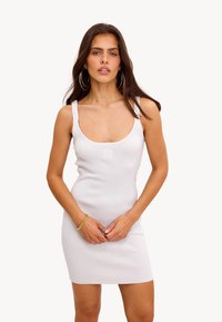 Robe blanche ajustée avec un décolleté en bateau, fabriquée en tissu texturé. Présente une broderie discrète "LOVE" sur la poitrine et des bretelles fines.