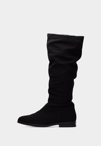 Bottes hautes noires jusqu'aux genoux en tissu lisse avec un design décontracté. Elles présentent un bout arrondi et un talon bas et plat pour plus de stabilité.