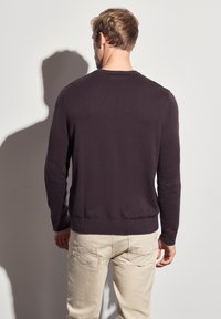 Dunkellila Rundhalspullover aus weichem Stoff, mit langen Ärmeln, einem eng anliegenden Taillenbund und einer glatten Textur.