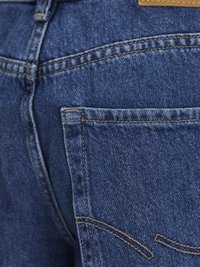 Denim jeans v modrem odtenku, s kontrastnim šivom in zadnjim žepom z dekorativnimi šivi. Vključuje usnjeno oznako na pasu.