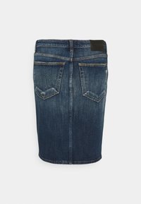 Jeanskjol i mörkblått med en figurnära passform, bakfickor och en märkespatch i svart läder vid midjan. Slät textur.