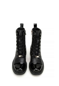 Black ankle boots with a glossy patent toe cap, lace-up design, and side zipper. Textured leather with a slight sheen and metal accents.