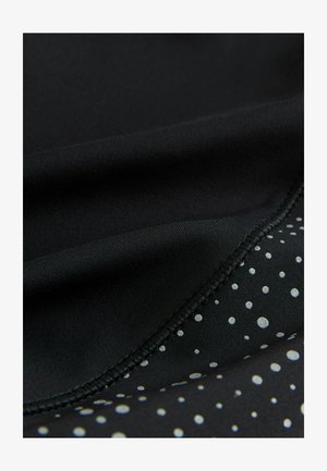 Sort stof med en glat tekstur, der har en mønstersektion med sølvprikker på en mørk baggrund, og kontrasterende sømdetaljer.