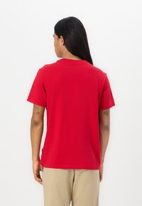 Camiseta de algodón roja con mangas cortas y cuello redondo, con una textura suave. Vista desde la parte de atrás, mostrando un ajuste relajado.