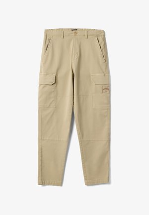 Pantaloni cargo beige con tasche frontali inclinate, tasche laterali con patta, chiusura con bottoni e una toppa cucita sulla tasca della coscia destra.