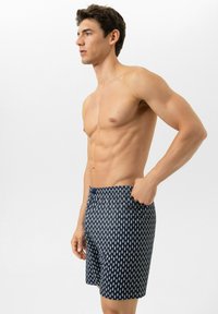 Donkerblauwe zwembroek met een wit geometrisch patroon, een elastische tailleband en zijzakken, gemaakt van lichtgewicht, sneldrogende stof.