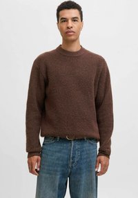 Bruin geribbeld gebreid sweater met een ronde hals, lange mouwen en een relaxte pasvorm, gecombineerd met blauwe denim jeans en een brown riem.